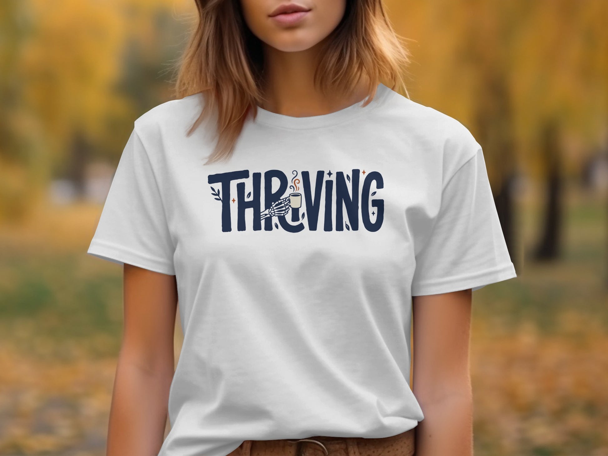 White t-shirt with "THRVING" text and skeleton hand holding coffee mug.